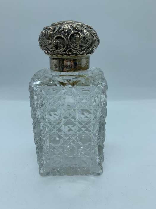 A cut glass scent bottle with hallmarked silver repousse lid