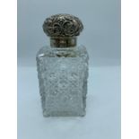 A cut glass scent bottle with hallmarked silver repousse lid