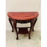 An Oriental cherry wood half moon carved side table with lower shelf