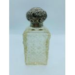 A cut glass scent bottle with hallmarked silver repousse lid