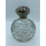 A cut glass scent bottle with hallmarked silver repousse lid