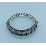 A Silver bangle set with sapphires, emeralds and rubies