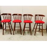 Four mahogany bar stools with red fabric seats