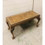 A Walnut topped coffee table with glass top on cabriole legs with ball claw feet, heavily carved