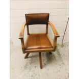 A Leather padded swivel chair in the arts and crafts style