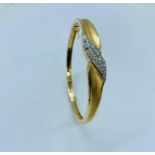 A 14ct yellow gold and diamond hinged bangle
