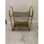 A brass tea trolley, two tier with smoked glass shelves.