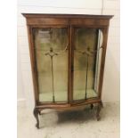 A Bow fronted ornate wooden glass panelled display cabinet on cabriole legs with two glass shelves