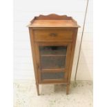 A Small hallway cupboard with drawers and glass door with shelves