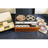 A reel to reel cassette deck by ultra with a selection of musical reels