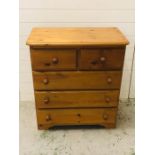 A modern pine chest of drawers two over three with round knobs