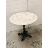 A white marble topped garden table on cast iron pedestal base with four feet