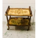 A two tier tea trolley on barley twist legs with castors with gold leaf detailing