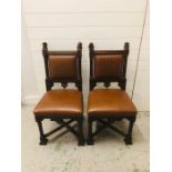 A pair of 17th century heavily carved chairs with head finials, leather seats and stud detailing