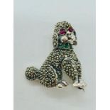 A silver brooch in the form of a poodle with ruby eye