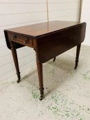 A mahogany Pembroke table with one drawer on brass castors