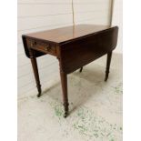 A mahogany Pembroke table with one drawer on brass castors