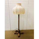 A large wooden floor lamp in the arts and crafts style with a fringed lamp shade