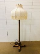 A large wooden floor lamp in the arts and crafts style with a fringed lamp shade