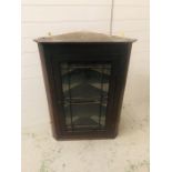 An oak wall corner cabinet with four scalloped shelves