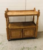 A pine sideboard with open shelf top and two small cupboards under on castors