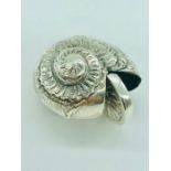 A silver ammonite shaped vesta case
