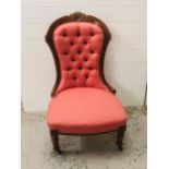 A salmon pink upholstered button back salon chair with carved wooden frame and legs on castors