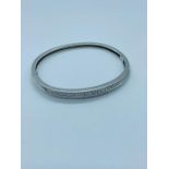 A 14ct white gold bangle with 52 small diamonds set in two lines. (16.3g)