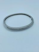 A 14ct white gold bangle with 52 small diamonds set in two lines. (16.3g)