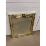A geometric design square brass framed mirror