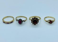 A selection of four 9ct gold rings all with rubies in a variety of settings.