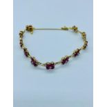 A Diamond and ruby bracelet in an 18ct gold setting with flowers in ruby with diamond links and