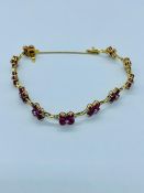 A Diamond and ruby bracelet in an 18ct gold setting with flowers in ruby with diamond links and