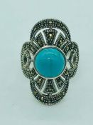 A silver ring set with marcasites and turquoise panel