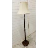 A mahogany turned standard lamp with cream shade