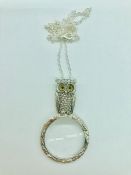 A silver owl magnifying glass on silver chain