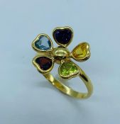 An 18ct multi stone daisy ring with aquamarine, peridot, citrine, ruby, amethyst