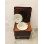 A commode with original pot with lid and handle