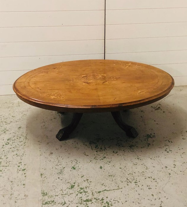 An oval coffee table of Victorian origins with a marquetry inlaid top on a modified base