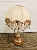 A lamp with a porcelain lady based and beaded fringed shade