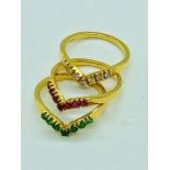 A set of three yellow gold wishbone style rings set with emeralds, rubies and diamonds