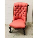 A salmon pink upholstered button back slipper chair with ornate carved legs, front two on castors