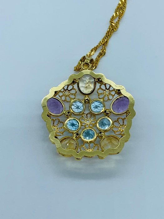 A pendant with semi precious stones to include amethyst, citrine and aquamarine, marked 750 on a