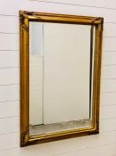 A large ornate gilt framed bevelled mirror (105cm x 75cm)