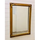 A large ornate gilt framed bevelled mirror (105cm x 75cm)