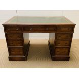 A double pedestal green leather topped desk with nine drawers