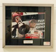 A Framed signed photograph of Lewis Hamilton with authentication stamp. Measures 39cms x 34cms.