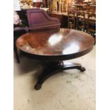 A large circular tilt top rosewood dining table on pedestal base with lion claw feet on brass
