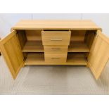 A sideboard unit with door to each end and three central drawers