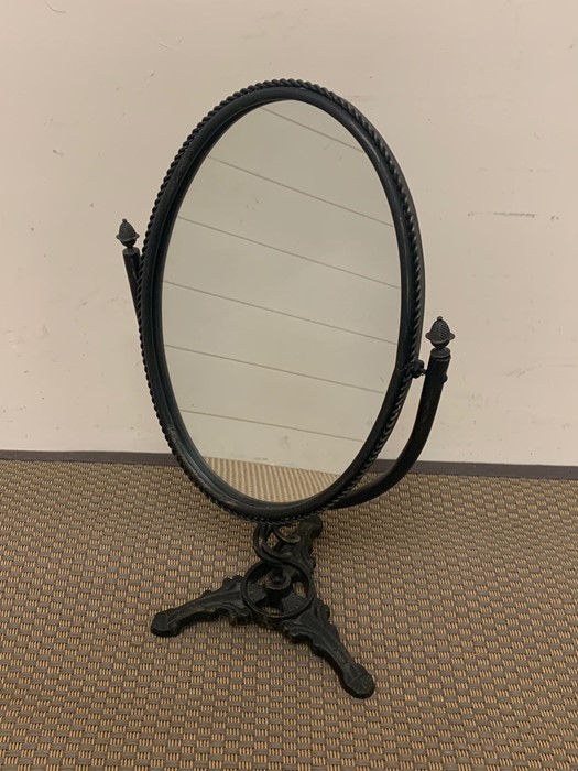 An oval table mirror on wrought iron frame